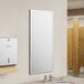 A commercial bathroom with an American Specialties, Inc. Plate Glass Mirror with a stainless steel Chan-Lok frame above a sink.