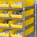 A metal shelving unit with Regency yellow shelf bins.