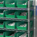 A shelf with Regency green plastic bins holding white objects.