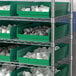 A shelf with Regency green bins filled with white objects.