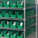 A metal shelving unit with green Regency shelf bins.