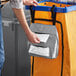 A man using a Lavex double pocket trash bag dispenser to put a bag in a trash can.