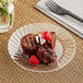 A WNA Comet clear plastic plate with brownies and raspberries on a table.
