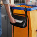 A man holding a Lavex black single pocket trash bag dispenser.