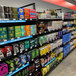 A shelf of liquor and beverages with a B-O-F Corporation VersaRack Beer Cave Gravity Flow Shelving Unit.