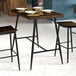 A Lancaster Table & Seating Mid-Century bar height table with plates and forks on it.