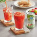 A close up of a Ruby Kist Vegetable Juice can on a table with a glass of ice and a straw.