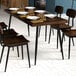 A Lancaster Table & Seating butcher block table with espresso finish and chairs with black frames set with plates and forks.