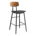 A Lancaster Table & Seating black metal barstool with a black vinyl padded seat and wood backrest.