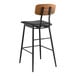 A Lancaster Table & Seating black barstool with a black vinyl seat and wood backrest.