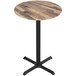 A close up of a Holland Bar Stool EuroSlim round wooden table with a black base.