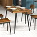 A Lancaster Table & Seating black standard height table base with a wooden top and four chairs.