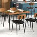 A Lancaster Table & Seating rectangular butcher block table with a vintage finish and black chairs set with plates and glasses.