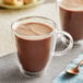 A glass mug of Gourmet Hot Chocolate with a spoon.