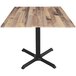 A Holland Bar Stool EuroSlim square table with a rustic wood top and black metal cross base.