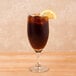 A Libbey tall iced tea glass with a straw and a lemon slice in it.