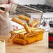 A woman using a Cambro amber plastic food pan with handle to cook food.