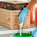 A person in blue gloves pouring SC Johnson Professional EZ Care floor coating into a box.