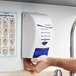 A white and blue SC Johnson Professional hand, hair, and body wash dispenser on a wall.