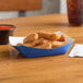 A blue paper food tray filled with fried food next to a drink.