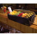 A San Jamar condiment bar with fruit and vegetable trays and green olives.