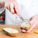 A person using a Vollrath Tater King Scooper to cut a potato.