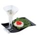 A black Fineline plastic cocktail plate with a stemware hole holding food next to a glass of liquid.
