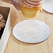 A person holding a cupcake over a silver round dessert board.