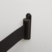 A black metal bracket on a white wall with a black tape attached.
