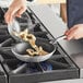 Mushrooms being cooked in a Vollrath Wear-Ever aluminum non-stick fry pan on a stove.