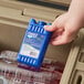 A hand holding a Lifoam Freez Pak Mini with a blue bottle in a cooler.