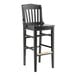 A black wooden Lancaster Table & Seating school house bar stool.