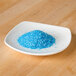 A small white plate with blue Rokz crystals on it.