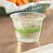 A World Centric compostable plastic cup with ice water on a table.