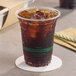 A 14 oz. clear compostable plastic cold cup filled with iced soda.