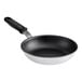 A close-up of a black Vollrath Wear-Ever frying pan with a white interior and black silicone handle.