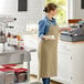 A woman in an Acopa Ashville Sage Linen Adjustable Bib Apron holding a cup and saucer.