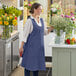 A woman wearing an Acopa Ashville Ocean Linen Smock Bib Apron standing in a flower shop.