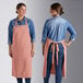 Two women wearing Acopa Ashville mauve bib aprons.