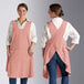 Two women wearing Acopa Ashville mauve linen smock bib aprons with pockets.