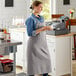 A woman in an Acopa Ashville linen bib apron holding a cup of coffee.