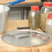 A Vollrath aluminum pan with a domed lid on a table with a blue Torogard handle.