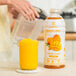 A woman pouring Smartfruit Mellow Mango beverage mix into a blender.
