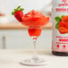 A glass of Smartfruit Summer Strawberry smoothie with strawberries on top.