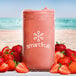 A pink strawberry smoothie in a Smartfruit Summer Strawberry container on a beach.