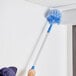 A person using a Lavex cobweb duster to clean a wall.