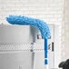 A Lavex Flex Wand Duster with a blue chenille sleeve attached to a metal pole.