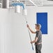 A man using a Lavex 24" Flex Wand Duster with Chenille Sleeve to clean a ceiling.