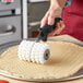 A person using a Choice dough docker with pointed wheels to cut dough.