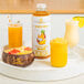 A tray with a glass of Smartfruit Aloha Pineapple Puree next to a bowl of fruit.